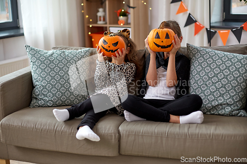 Image of girls in halloween costumes with pumpkins at home