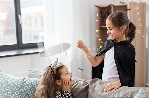 Image of girls in halloween costumes playing with spider