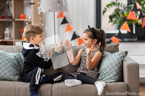 Image of kids in halloween costumes playing game at home