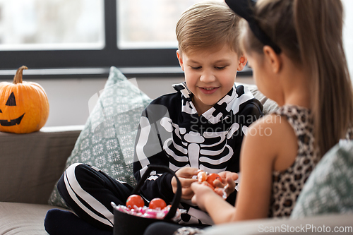 Image of kids in halloween costumes with candies at home