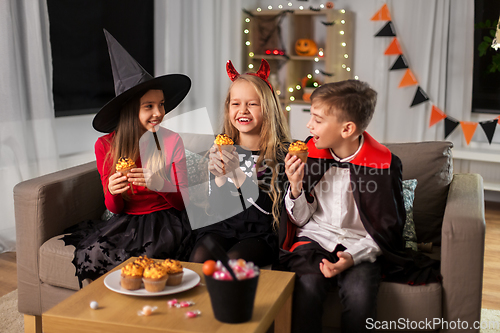 Image of kids in halloween costumes eating cupcakes at home