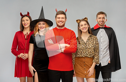 Image of happy friends in halloween costumes over grey