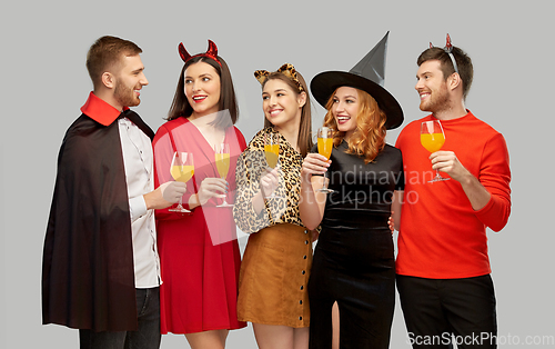 Image of happy friends in halloween costumes over grey