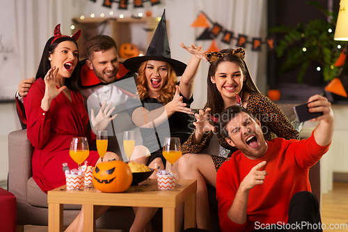 Image of happy friends in halloween costumes taking selfie