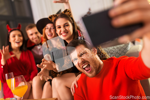 Image of happy friends in halloween costumes taking selfie