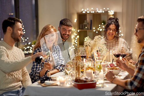 Image of happy friends with red wine at christmas party