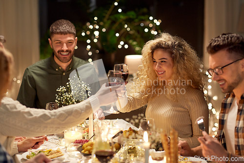 Image of happy friends drinking red wine at christmas party