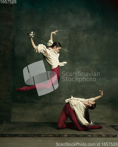 Image of Two young female ballet dancers like duelists with swords. Ballet and contemporary choreography concept. Creative art photo.