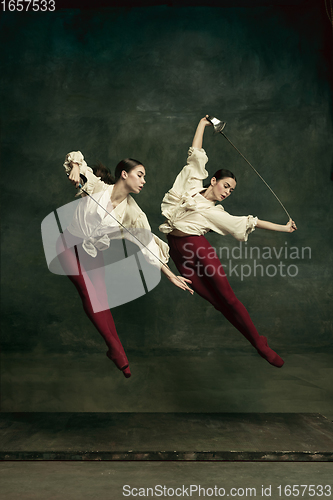 Image of Two young female ballet dancers like duelists with swords. Ballet and contemporary choreography concept. Creative art photo.