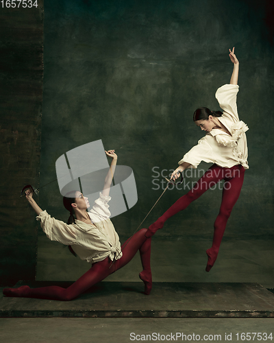 Image of Two young female ballet dancers like duelists with swords. Ballet and contemporary choreography concept. Creative art photo.