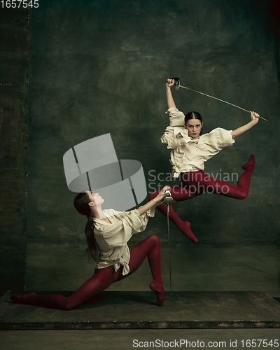 Image of Two young female ballet dancers like duelists with swords. Ballet and contemporary choreography concept. Creative art photo.