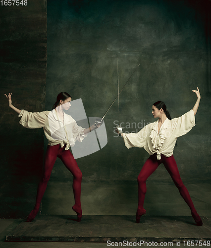 Image of Two young female ballet dancers like duelists with swords. Ballet and contemporary choreography concept. Creative art photo.