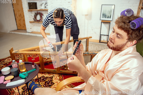 Image of Gender stereotypes. Wife and husband doing things unusual for their genders in social meanings