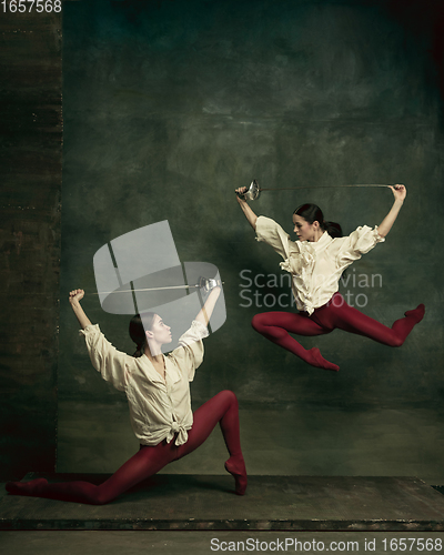 Image of Two young female ballet dancers like duelists with swords. Ballet and contemporary choreography concept. Creative art photo.