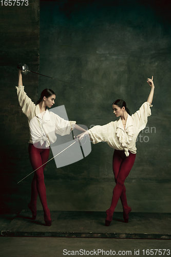 Image of Two young female ballet dancers like duelists with swords. Ballet and contemporary choreography concept. Creative art photo.