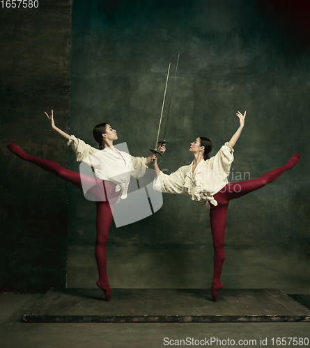 Image of Two young female ballet dancers like duelists with swords. Ballet and contemporary choreography concept. Creative art photo.