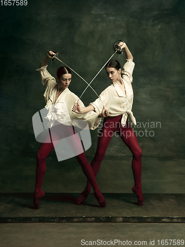 Image of Two young female ballet dancers like duelists with swords. Ballet and contemporary choreography concept. Creative art photo.