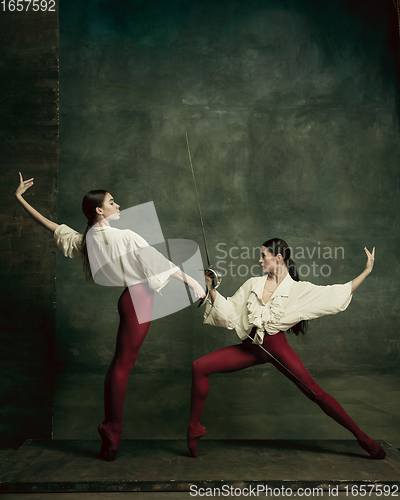 Image of Two young female ballet dancers like duelists with swords. Ballet and contemporary choreography concept. Creative art photo.