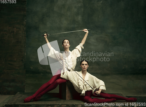 Image of Two young female ballet dancers like duelists with swords. Ballet and contemporary choreography concept. Creative art photo.