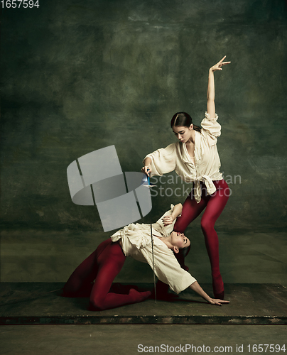 Image of Two young female ballet dancers like duelists with swords. Ballet and contemporary choreography concept. Creative art photo.