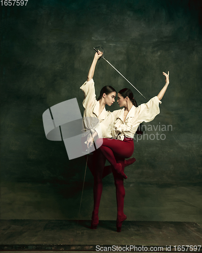 Image of Two young female ballet dancers like duelists with swords. Ballet and contemporary choreography concept. Creative art photo.