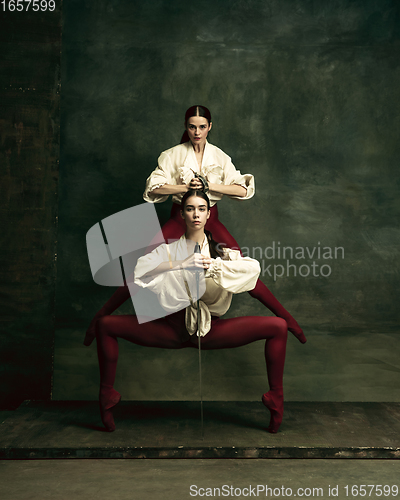 Image of Two young female ballet dancers like duelists with swords. Ballet and contemporary choreography concept. Creative art photo.