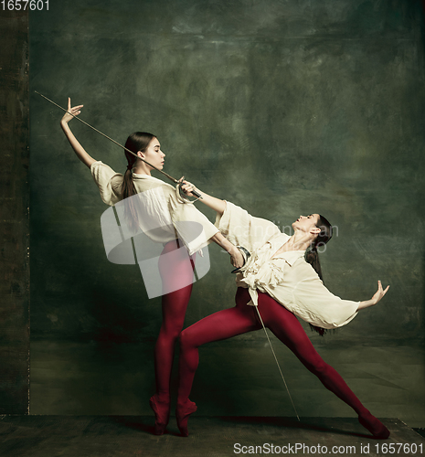 Image of Two young female ballet dancers like duelists with swords. Ballet and contemporary choreography concept. Creative art photo.