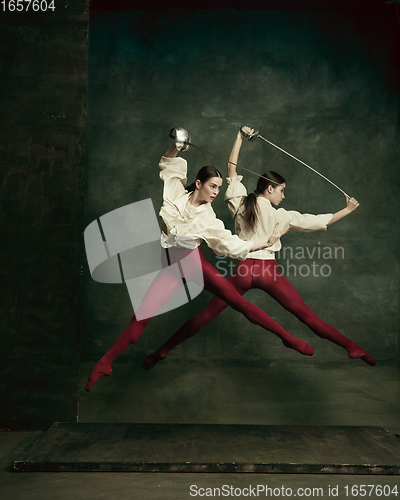 Image of Two young female ballet dancers like duelists with swords. Ballet and contemporary choreography concept. Creative art photo.