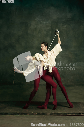 Image of Two young female ballet dancers like duelists with swords. Ballet and contemporary choreography concept. Creative art photo.