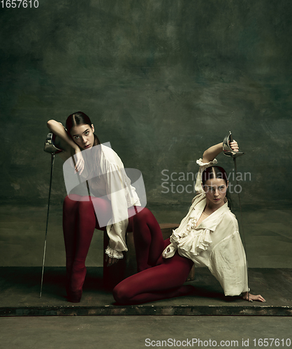 Image of Two young female ballet dancers like duelists with swords. Ballet and contemporary choreography concept. Creative art photo.