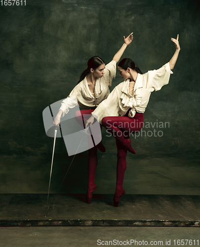 Image of Two young female ballet dancers like duelists with swords. Ballet and contemporary choreography concept. Creative art photo.