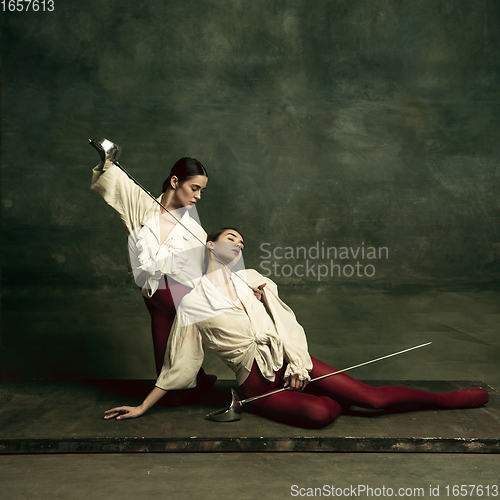 Image of Two young female ballet dancers like duelists with swords. Ballet and contemporary choreography concept. Creative art photo.