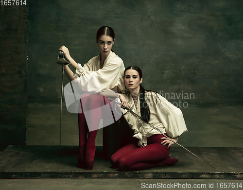 Image of Two young female ballet dancers like duelists with swords. Ballet and contemporary choreography concept. Creative art photo.