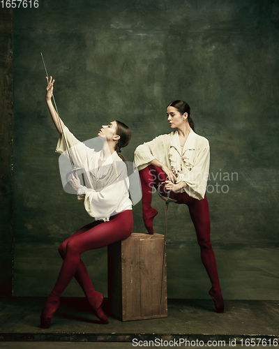 Image of Two young female ballet dancers like duelists with swords. Ballet and contemporary choreography concept. Creative art photo.