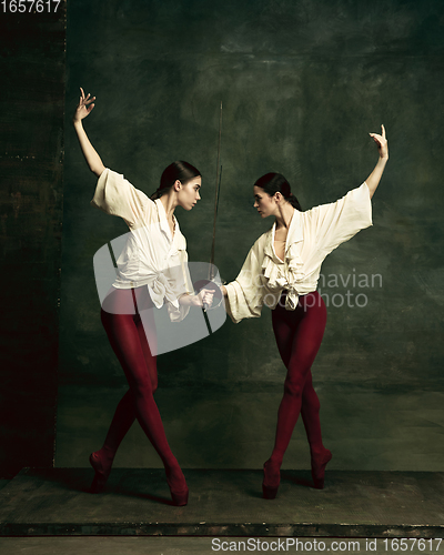 Image of Two young female ballet dancers like duelists with swords. Ballet and contemporary choreography concept. Creative art photo.