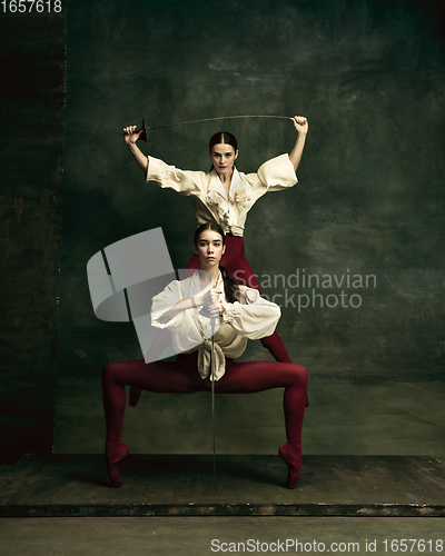 Image of Two young female ballet dancers like duelists with swords. Ballet and contemporary choreography concept. Creative art photo.