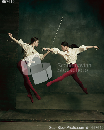 Image of Two young female ballet dancers like duelists with swords. Ballet and contemporary choreography concept. Creative art photo.