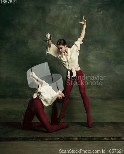 Image of Two young female ballet dancers like duelists with swords. Ballet and contemporary choreography concept. Creative art photo.