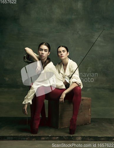 Image of Two young female ballet dancers like duelists with swords. Ballet and contemporary choreography concept. Creative art photo.