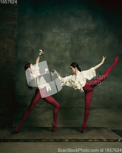 Image of Two young female ballet dancers like duelists with swords. Ballet and contemporary choreography concept. Creative art photo.