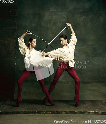 Image of Two young female ballet dancers like duelists with swords. Ballet and contemporary choreography concept. Creative art photo.