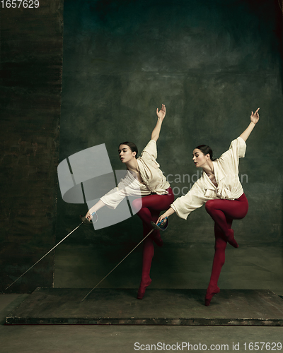 Image of Two young female ballet dancers like duelists with swords. Ballet and contemporary choreography concept. Creative art photo.