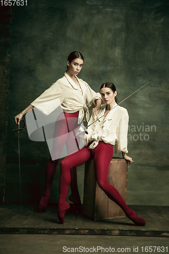 Image of Two young female ballet dancers like duelists with swords. Ballet and contemporary choreography concept. Creative art photo.