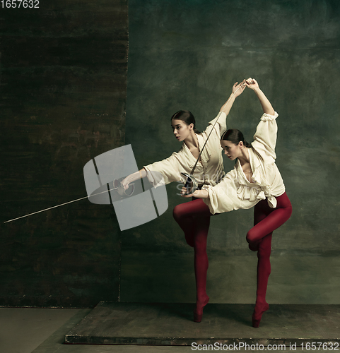 Image of Two young female ballet dancers like duelists with swords. Ballet and contemporary choreography concept. Creative art photo.