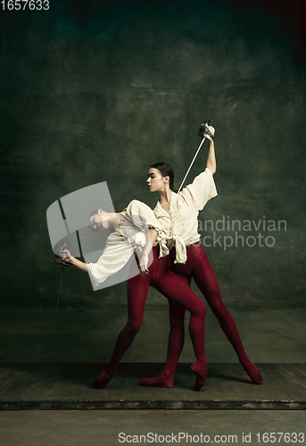 Image of Two young female ballet dancers like duelists with swords. Ballet and contemporary choreography concept. Creative art photo.