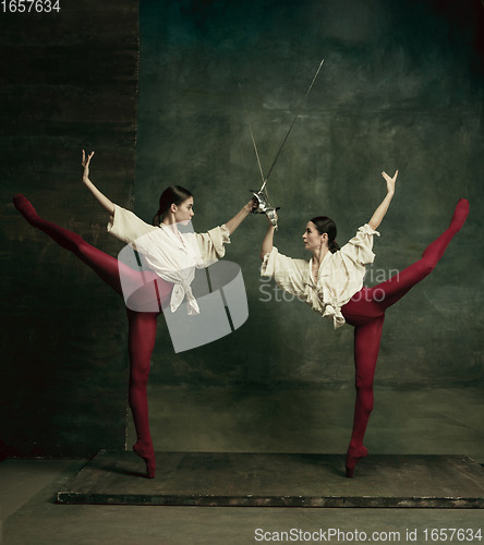 Image of Two young female ballet dancers like duelists with swords. Ballet and contemporary choreography concept. Creative art photo.