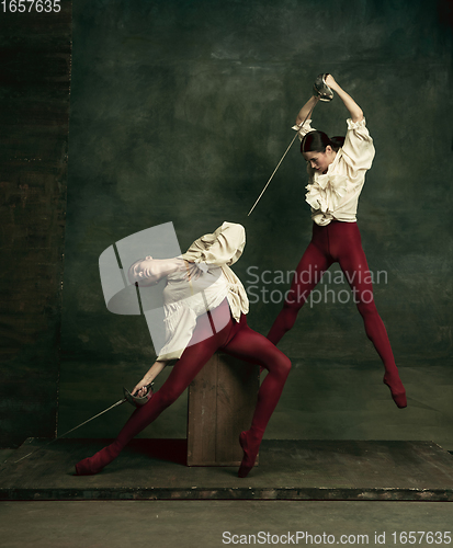 Image of Two young female ballet dancers like duelists with swords. Ballet and contemporary choreography concept. Creative art photo.