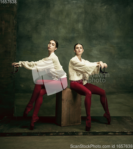 Image of Two young female ballet dancers like duelists with swords. Ballet and contemporary choreography concept. Creative art photo.