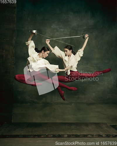 Image of Two young female ballet dancers like duelists with swords. Ballet and contemporary choreography concept. Creative art photo.