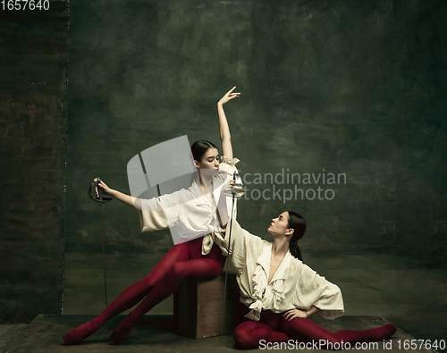 Image of Two young female ballet dancers like duelists with swords. Ballet and contemporary choreography concept. Creative art photo.